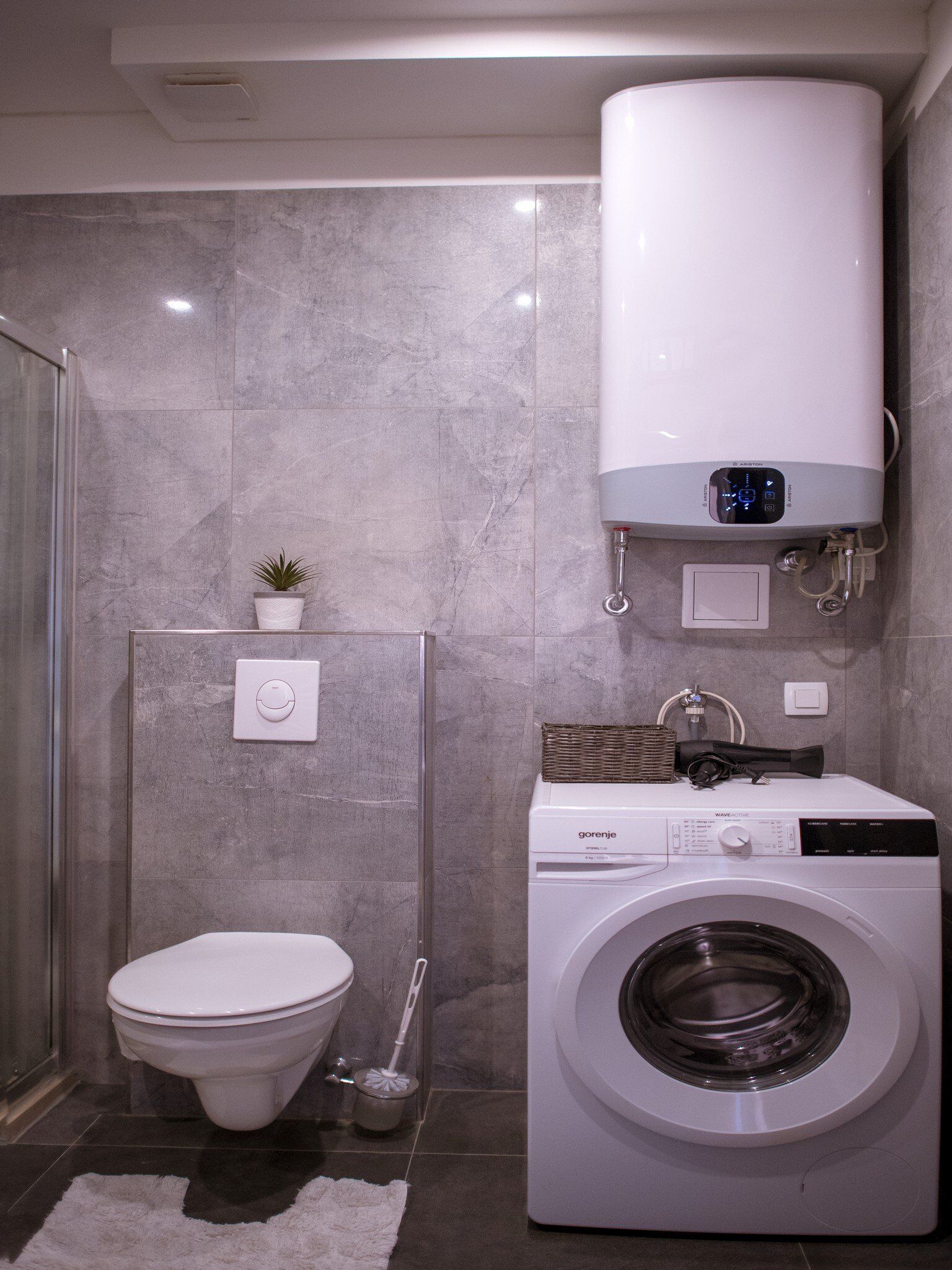 Un bagno piccolo ma funzionale, con il water, una lavatrice e un termosifone a parete.