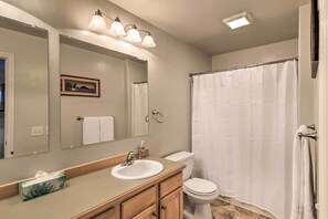 Un baño con lavabo, espejo e inodoro.