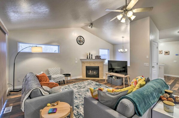 Una sala de estar moderna con chimenea, ventilador de techo y televisor.