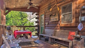Eine rustikale Holzhütte mit Veranda, einem Tisch mit roter Tischdecke und einer Bank mit rotem Kissen.
