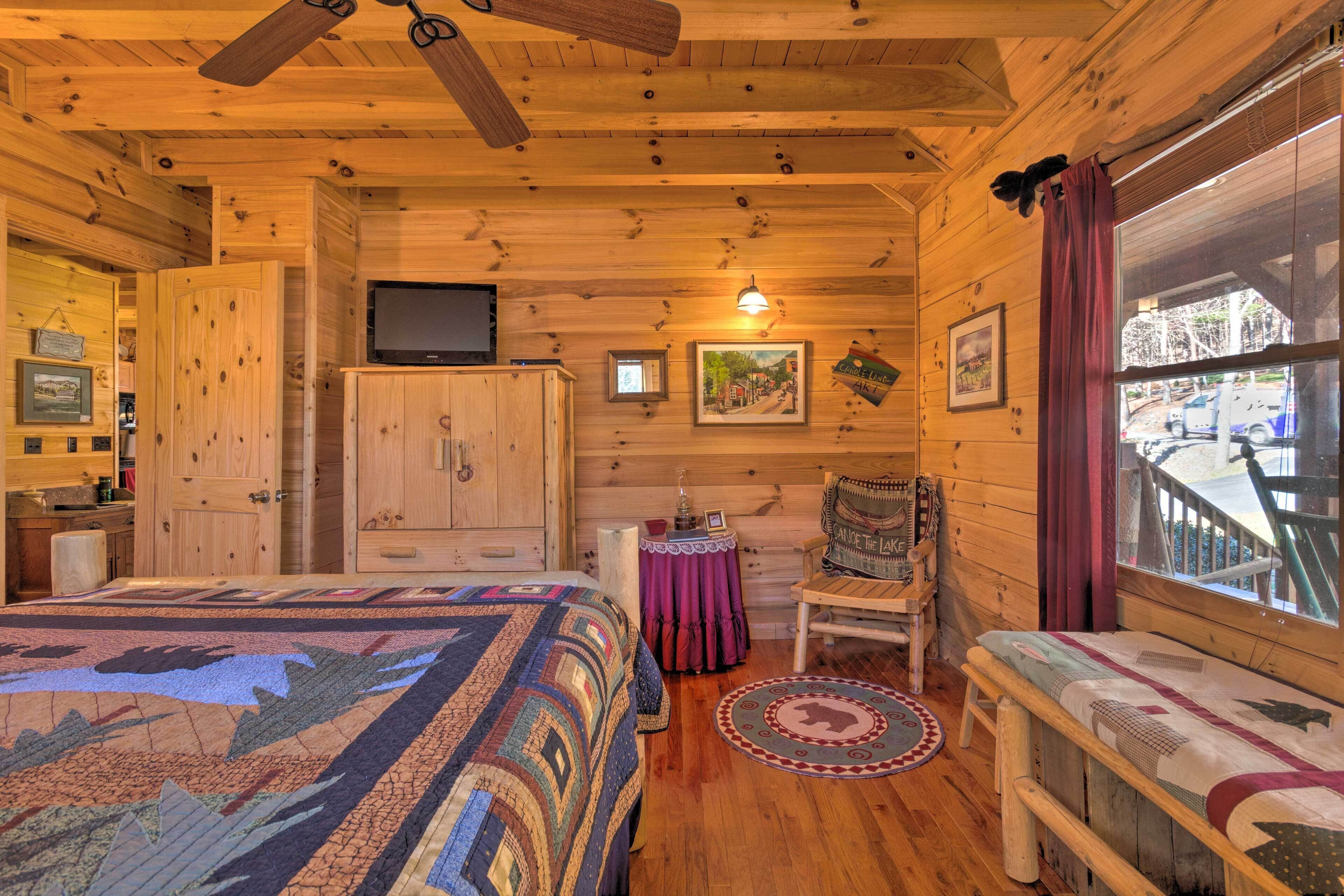 Een gezellig blokhutkamer met een bed, een stoel, een televisie en een raam met uitzicht.