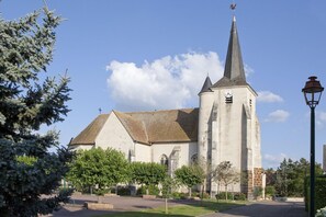 Situated in a serene setting, this traditional church features a prominent steeple and clock tower surrounded by a well-maintained garden.