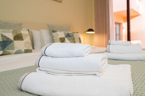Una cama bien hecha con toallas blancas dobladas y una colcha verde con textura.