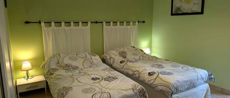 Um quarto com duas camas, uma mesa de cabeceira com luminária e um quadro pendurado na parede.