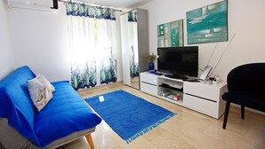 A living room with a sofa, a flat-screen TV, a white entertainment unit, and artwork on the wall. - Apartment Zorica (Supetar)