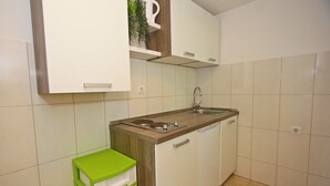 A compact kitchen with a sink, stove, and cabinets. - Apartment Zorica (Supetar)