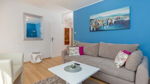 A living room with a sofa, a coffee table, a mirror, and a painting on the wall. - Apartment Fiorella (Dubrovnik)