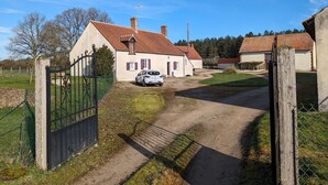 Een landhuis met een geplaveid pad dat leidt naar een hekwerk.