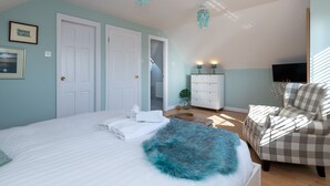 A bedroom with a bed, a dresser, a chair, and a television.