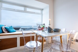 A dining area with a table and chairs, a window with a view, and a candle on the table.