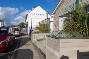 A street view with a building labeled 'FISH & CHIPS' and a sign for 'JANET BELL.' - Sunset View: Two bedroom pet-friendly holiday apartment (Rhosneigr)