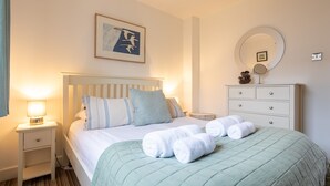 A neatly made bed with a green quilt, a bedside lamp, and a framed picture on the wall. - Headline (VRBO): Sunset View : Pet-Friendly 2‑Bed Apartment with Bay Views in Rhosneigr | Managed by (Rhosneigr)