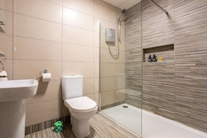 A modern bathroom with a shower, toilet, and sink.