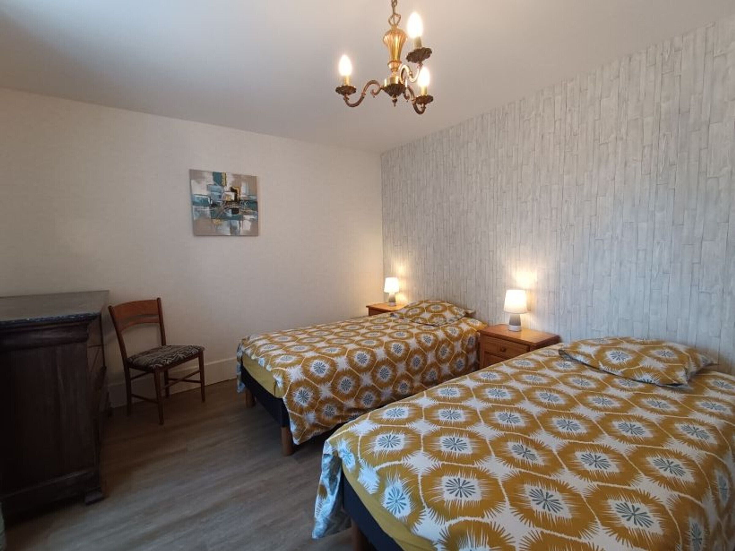 A bedroom with two beds, a desk, and a chair.