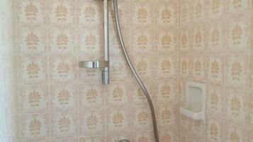 A shower with a handheld showerhead and a wall-mounted faucet.