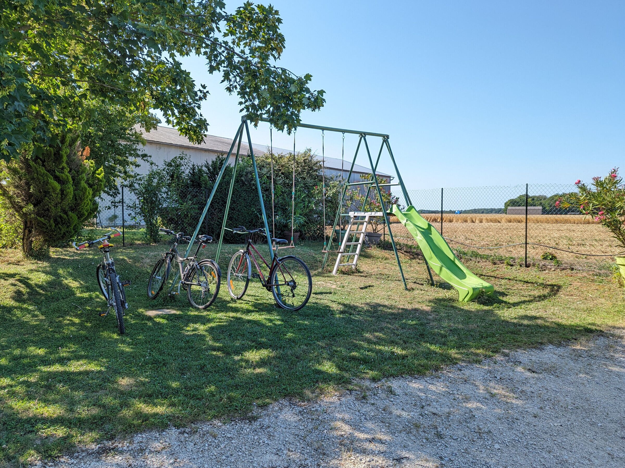 Une aire de jeux avec des balançoires, un toboggan et des vélos garés à proximité.