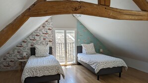 Une chambre avec deux lits, un plancher en bois et un plafond en pente.