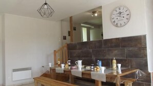 Une cuisine moderne avec un banc en bois, un luminaire suspendu et une horloge au mur.