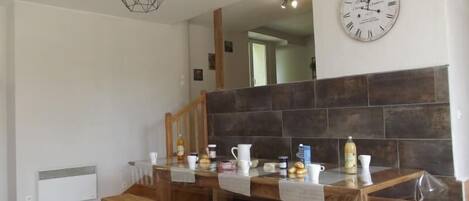 A modern kitchen with a wooden bench, a hanging light fixture, and a clock on the wall.