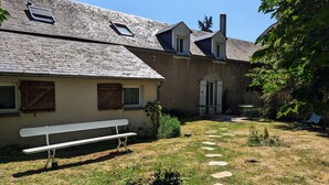 Un bâtiment doté d’un toit en pente, d’un banc et d’un jardin agrémenté de pierres plates servant de pas.