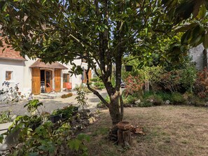 A rustic house with a garden, a wooden door, and a small outdoor seating area. - Spacious Vintage Cottage in Loire Valley: Village Charm, Garden, Pets Welcome (Tavers)
