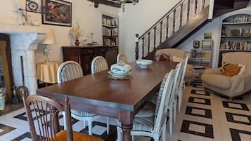 Un comedor con mesa de madera, sillas y una araña.