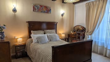A bedroom with a wooden bed, bedside lamps, a dresser, a mirror, and a painting on the wall.