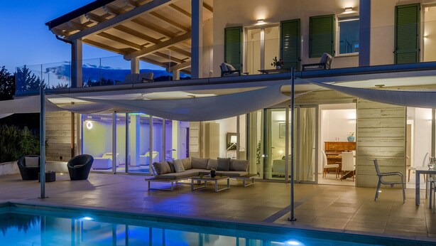 Ein modernes, zweistöckiges Haus mit Swimmingpool, Außenbereich zum Sitzen und einem Klavier im Wohnbereich.