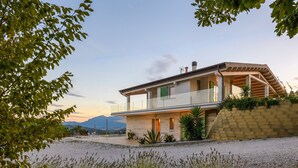 Ein zweistöckiges Haus mit Balkon, Steinmauer und Kiesweg.