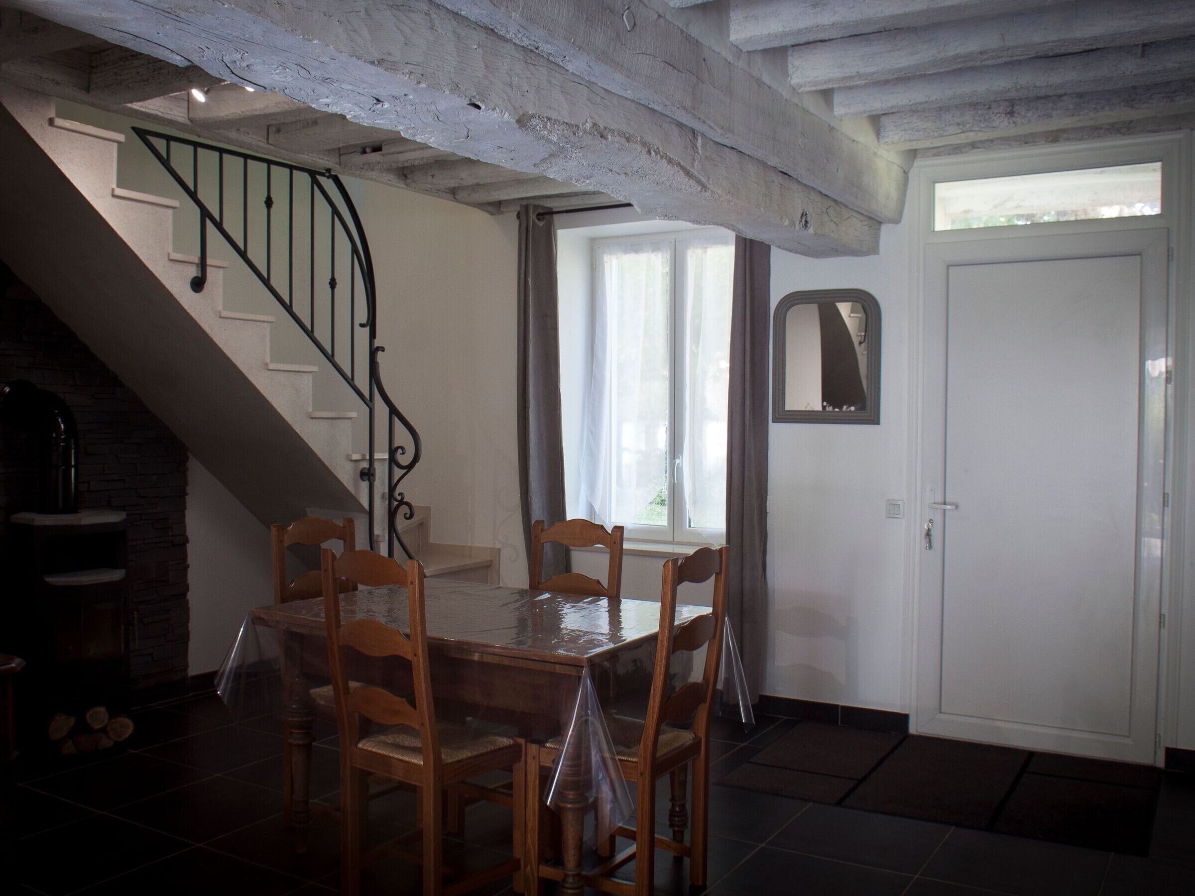 Un espace repas comprenant une table et des chaises, un escalier, une porte et une fenêtre.