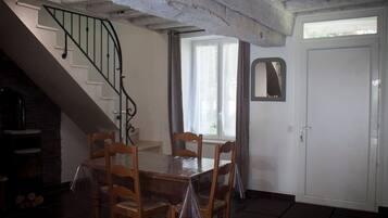 Un espace repas comprenant une table et des chaises, un escalier, une porte et une fenêtre.