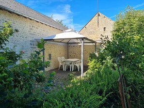 Een stenen gebouw met een overdekte patio, inclusief een tafel en stoelen.