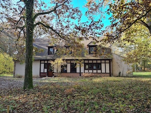 A traditional half-timbered house with a sloped roof, a visible chimney, and a front porch.