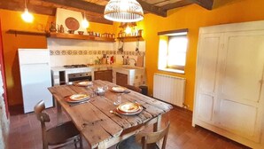 Eine rustikale Küche mit einem Holztisch, gedeckt für ein Essen, einem Kühlschrank und einem Fenster mit Blick.