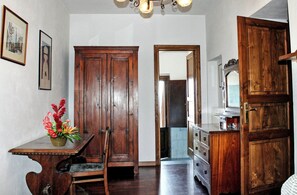 Une pièce comprenant un meuble en bois, un miroir et une petite table agrémentée d’un arrangement floral.