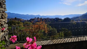 Ein Balkon mit einer Steinmauer, einem Metallgeländer und rosa Blüten im Vordergrund.