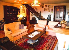 Un salon avec un canapé, des fauteuils, une table basse et un escalier.