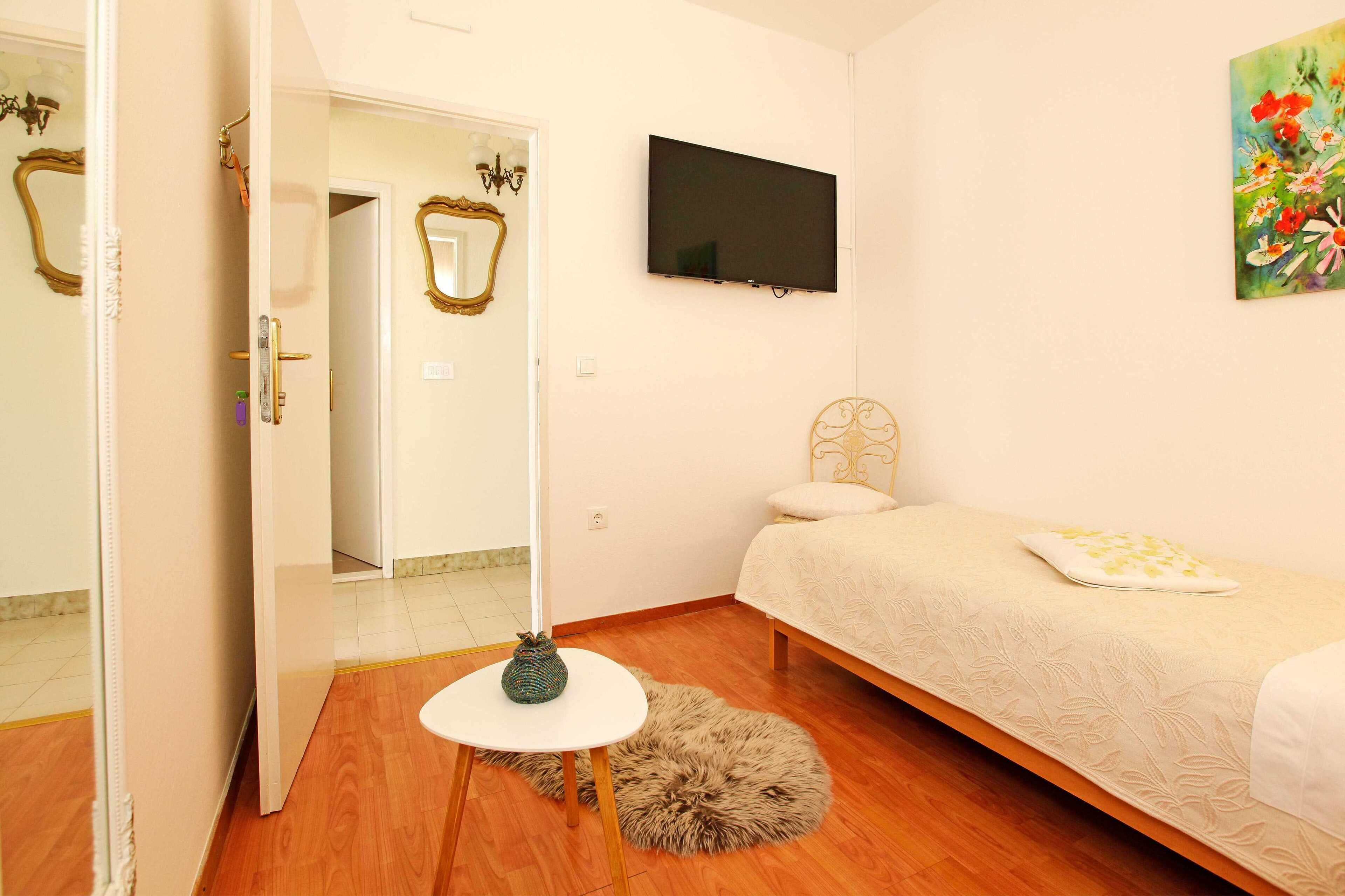 A bedroom with a bed, a TV, a painting, and a small table.