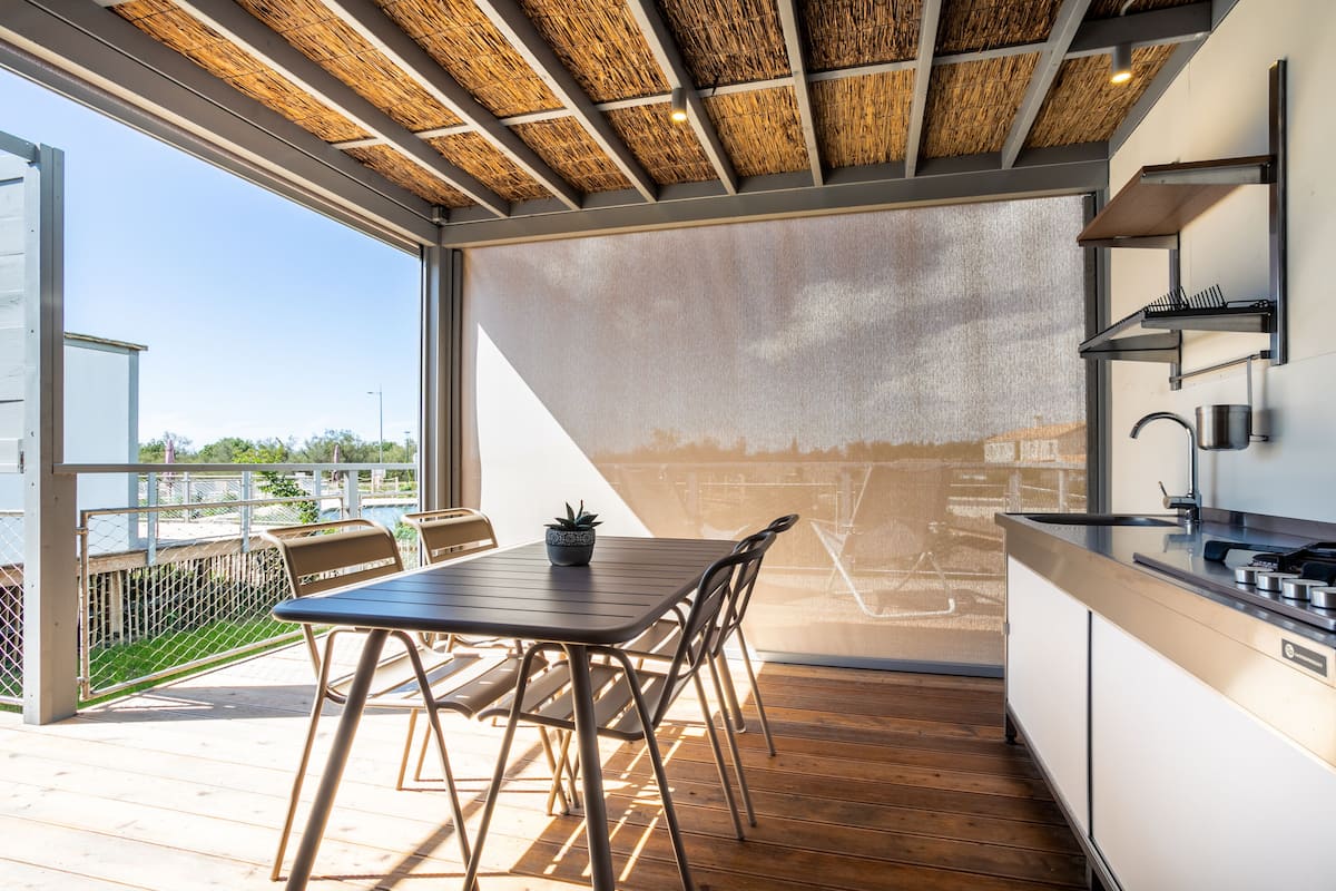 Une cuisine moderne dotée d’une grande fenêtre, d’un plancher en bois et d’un coin repas avec une table et des chaises.
