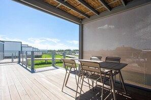 Eine moderne Terrasse im Freien mit Holzboden, Metallstühlen und einem Tisch.