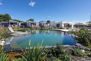 Een modern hotel met een zwembad, terras en een verzorgde tuin.