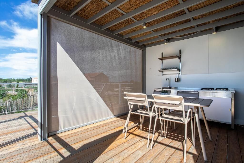 Una cocina moderna al aire libre con comedor, ventanas amplias y vistas del paisaje circundante.