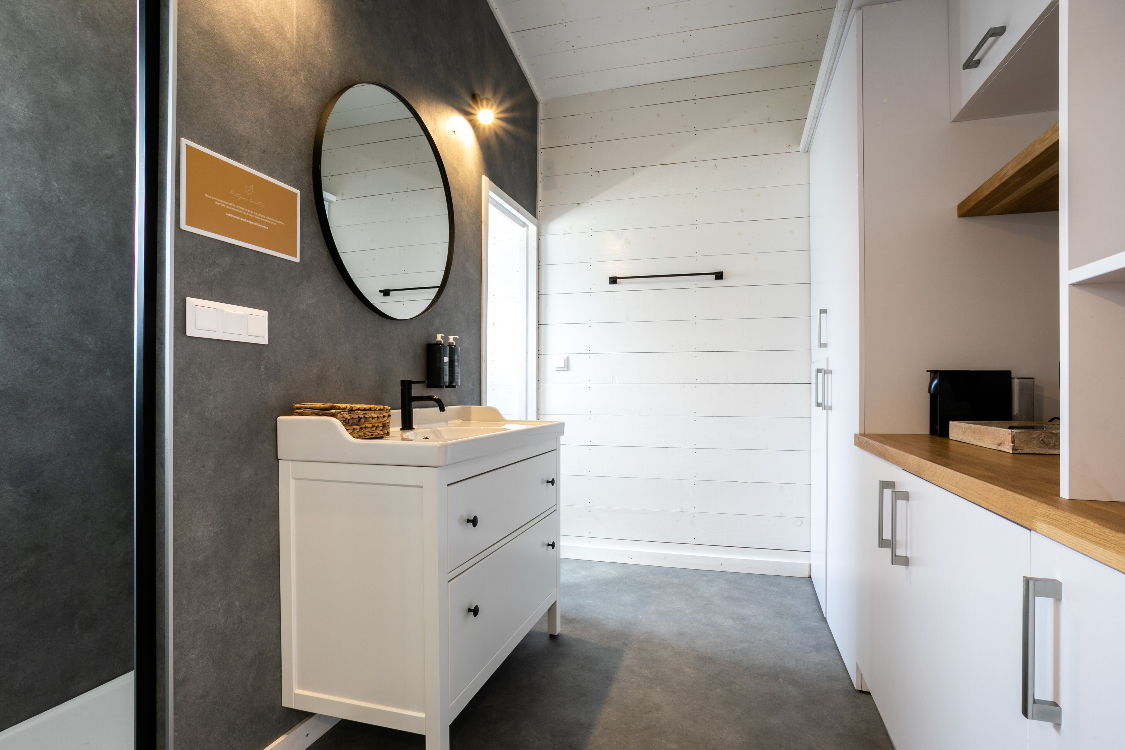 Un baño moderno con tocador blanco, un espejo grande y encimera de madera.
