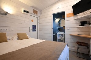 Ein Schlafzimmer mit Bett, Schreibtisch, Stuhl, Spiegel und Tür.