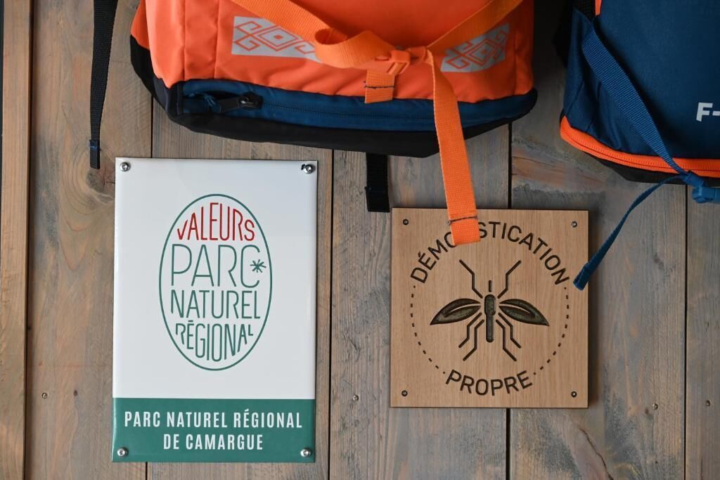Señal para el Parque Natural Regional de Camargue y una placa de madera con una ilustración de insecto.