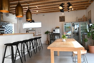 Una cocina moderna con una mesa de madera, taburetes tipo barra negros y lámparas colgantes.