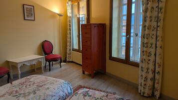 A bedroom with a bed, a chair, a dresser, and a window with curtains.