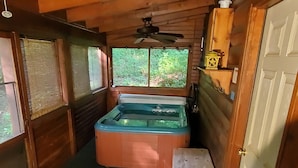 Una habitación pequeña y acogedora con detalles de madera, un jacuzzi, una mesita y una puerta.