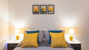 A neatly arranged bedroom with a bed, two bedside tables with lamps, and three framed pictures on the wall. - Brand new luxury apartment with stunning sea views (Aberystwyth)