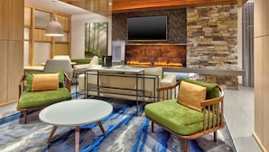 A modern living room with a stone fireplace, a flat-screen TV, and comfortable seating. -  Fairfield by Marriott Inn & Suites Knoxville Airport Alcoa (Alcoa)